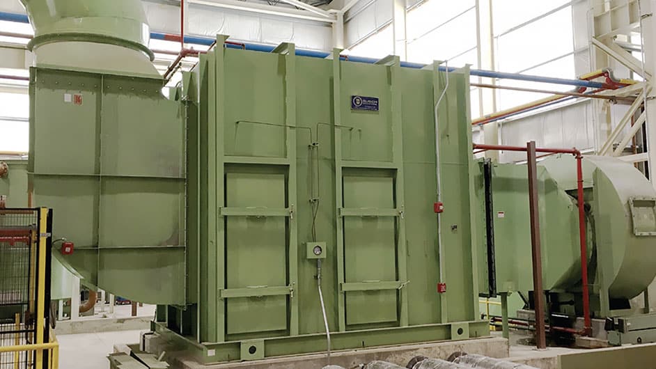 A large, green painted high-efficiency horizontal mist elimination unit is installed inside of an industrial facility to remove particulates.